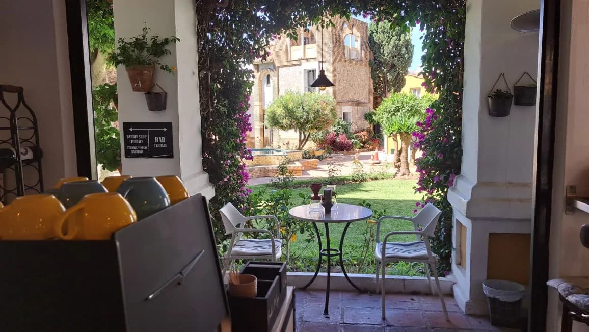 View from the counter towards the garden: yellow cups stacked in the foreground and a table with chairs under the bougainvillea